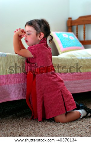 A young girl kneeling down saying a prayer