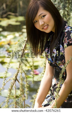 Brunette asian girl sitting at the lakeside.