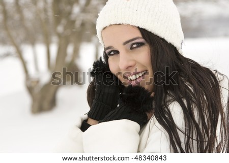 Smiling woman in snow with hands on face