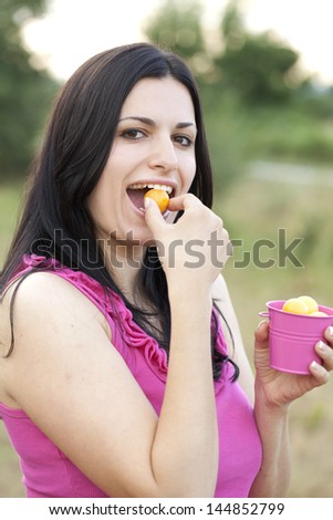 Attractive woman eating yellow plums