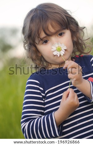 Beautiful little girl smelling a flower