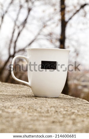 White mug with a black rectangle outdoors
