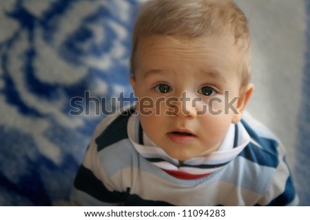 Surprised small boy on blue-white blanket background