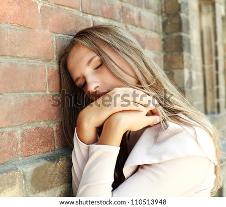 Portrait of a sad young girl put her head on a brick wall
