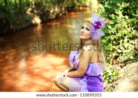 Portrait glamorous young blonde girl,posing in violet dress on the bank of red river
