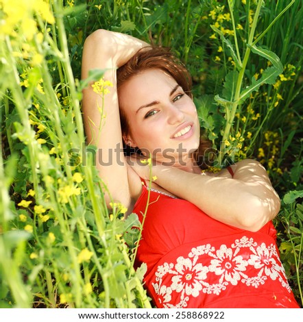 Young woman relaxing on a beautiful green meadow, dreaming in summer time