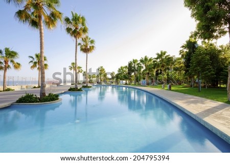 LIMASSOL, CYPRUS - 30 MAY 2014: A view of Molos Promenade on the coast of Limassol city in Cyprus. A view of the walk path surrounded by palm trees, pools of water, grass and the Mediterranean sea.