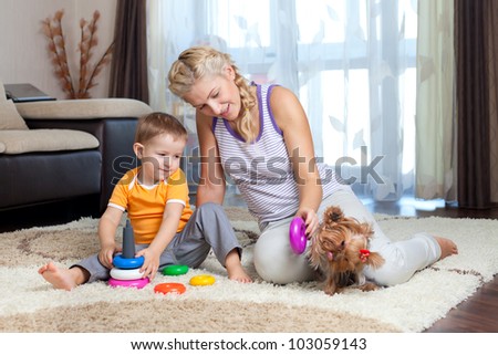 mother, child boy and pet dog playing toy together indoor