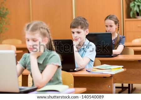 school kids using laptop at lesson