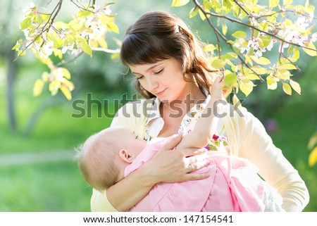 young mother breast feeding her baby girl in garden