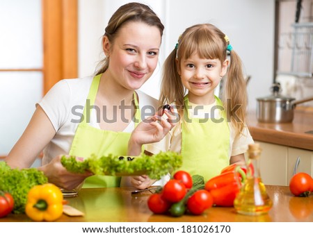 Young mother and her kid making vegetable salad