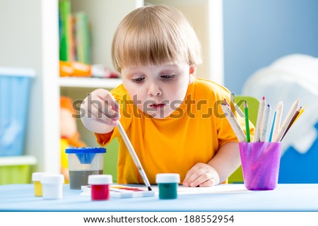 kid painting at table in children room