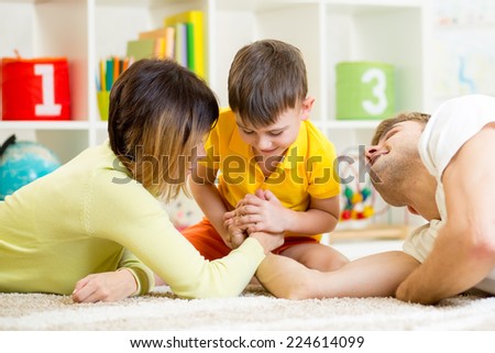 kid boy, his father and mother competing in physical strength