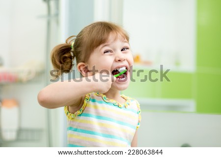 Funny child girl brushing teeth in bathroom