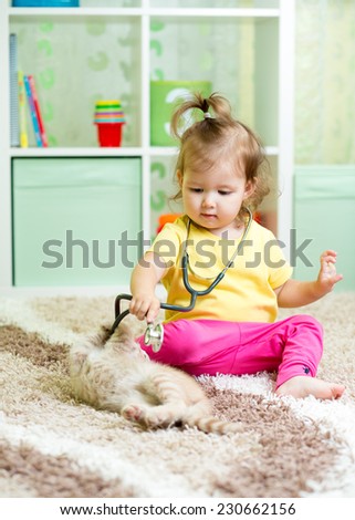kid girl plays doctor with kitten at home