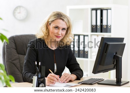 Middle-aged pretty business woman working at pc in office