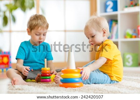 children brothers playing together in nursery at home