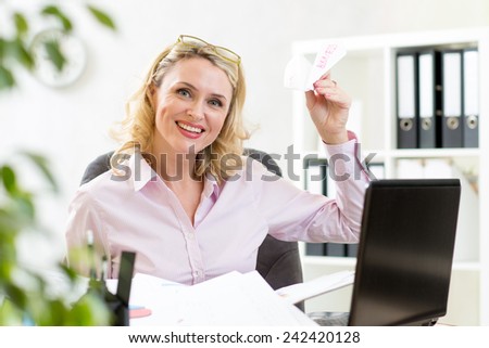 mature business woman throwing paper airplane in office