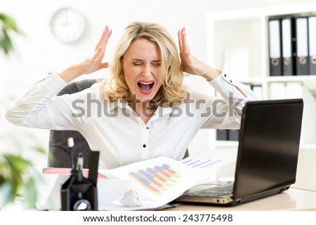 Stressed business woman screaming loudly at laptop in office