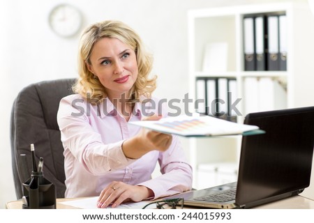 Smiling mature businesswoman giving paper or reports