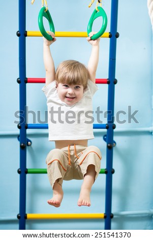child boy hanging on gymnastic rings at home