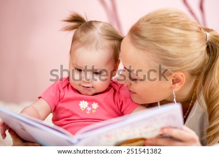 happy mother read a book to baby girl indoors