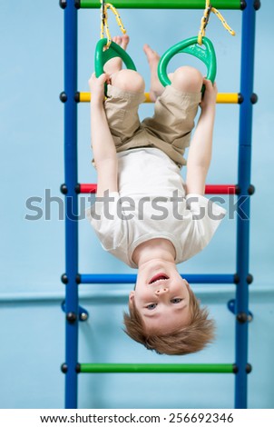 child boy hanging on gymnastic rings at home