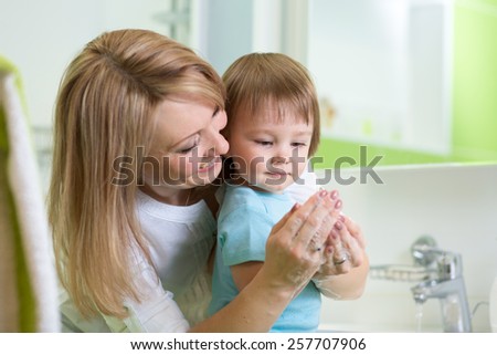 kid boy and mother washing hands with soap in bathroom