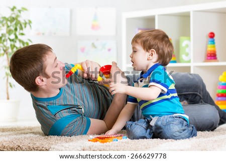Happy family dad and son play musical toys on floor