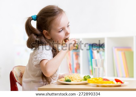 preschooler kid girl eating healthy food at home or kindergarten