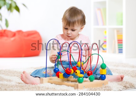 kid girl plays with educational toy indoors
