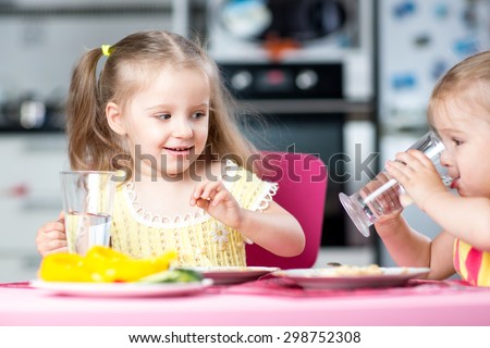 Cute little children drinking water at daycare or nursery