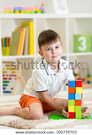 kid little boy playing with cubes toys in nursery at home or kindergarten