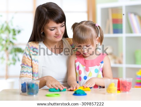Young pretty woman and kid playing with colorful clay molding different shapes