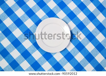 white round plate on blue checked tablecloth
