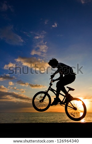 Silhouette of a man on bike jumping in the sunset