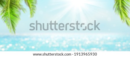 Panorama of blurred blue sky and sea with bokeh light and leaves of coconut palm tree. Landscape of tropical summer. Summer vacation concept.
