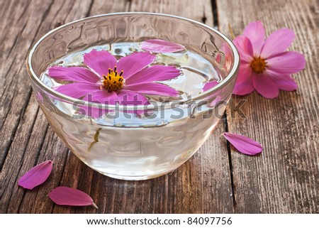 bowl of water and floating flower sitting on wooden table