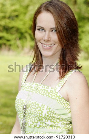 Smiling red headed woman in green environment