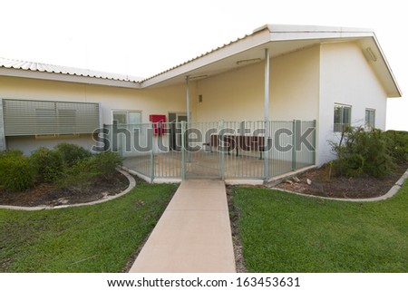 A small Australian house or building with a garden, fence and pavements.