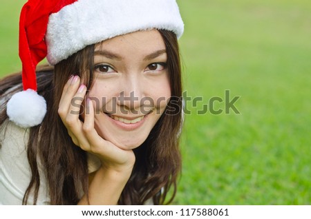 Beautiful young santa clause woman in christmas clothes smiling on the ground