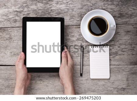 hand hold the empty tablet with note paper and coffee on the wooden table