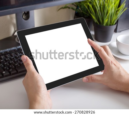 hands of a man holding blank tablet device over a workspace table
