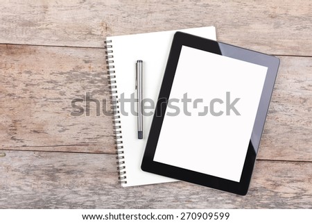 Tablet and notepad on a wooden desktop