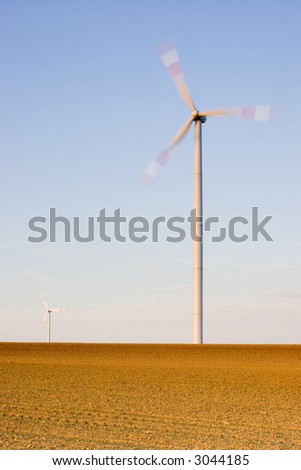 Two wind-turbines on a field at sunset. With long exposure time for motion blurred propellers of the wind-turbines.