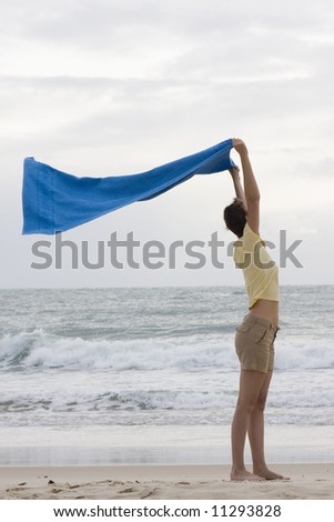 Woman holding a towel in the wind on a beach