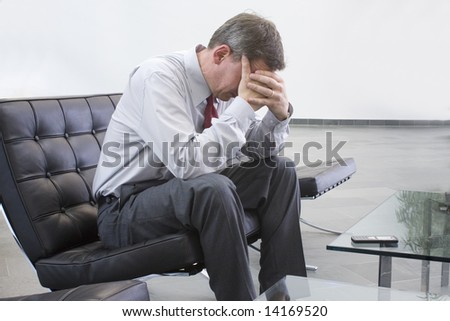 Tired businessman sitting on a chair in a lounge