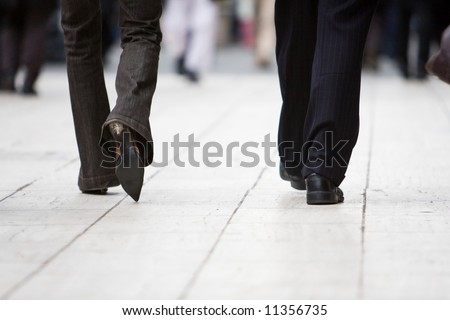 The legs of a business man and woman walking away from the camera