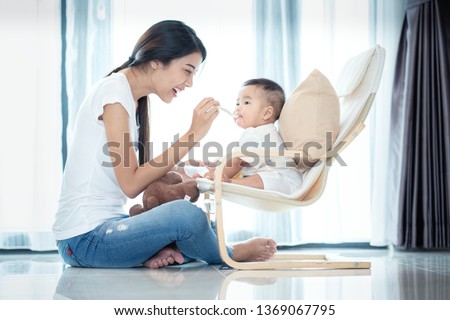 Similar – Image, Stock Photo Mom feeds her little son sitting on a chair in the kitchen