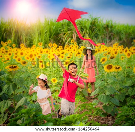 Family mother and son in summer playing with kite with sun flower garden